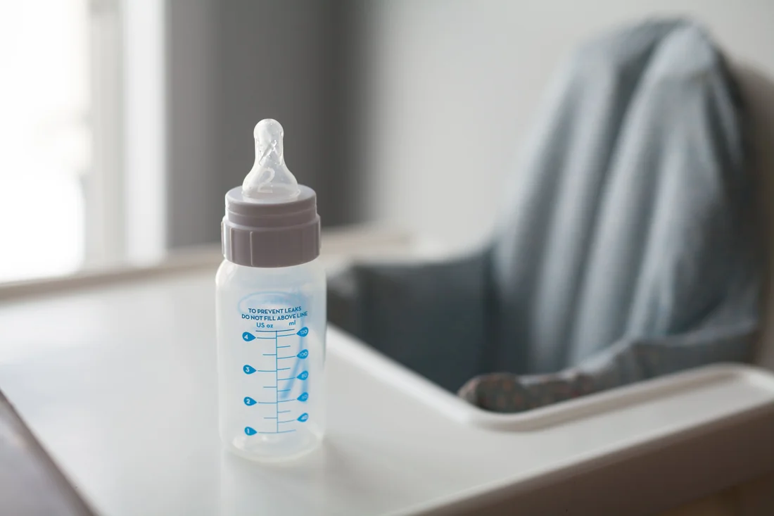 An empty baby bottle on a highchair tray